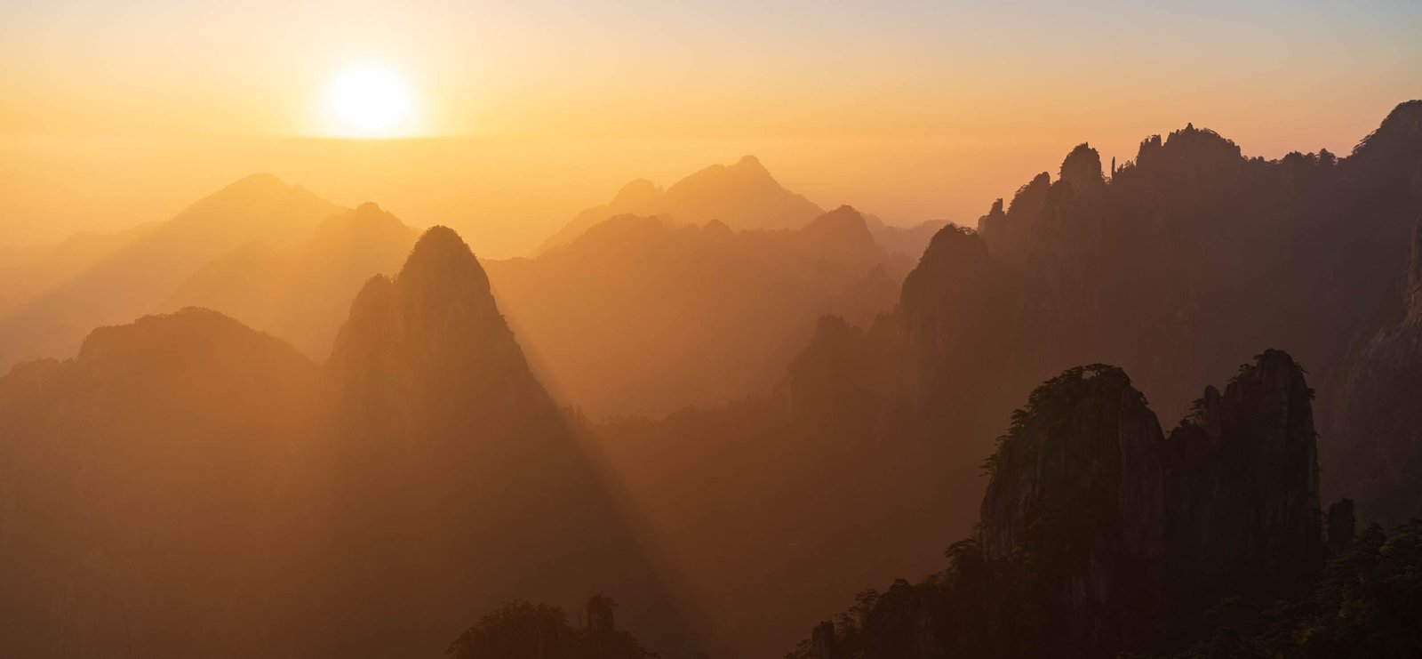Warm sunrise light reveals the layered peaks of Huangshan.