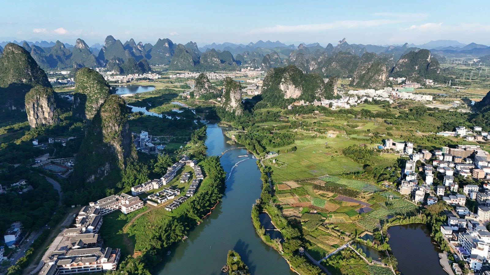 Sunlit karst peaks, fields and the winding river in Yangshuo, Guangxi.